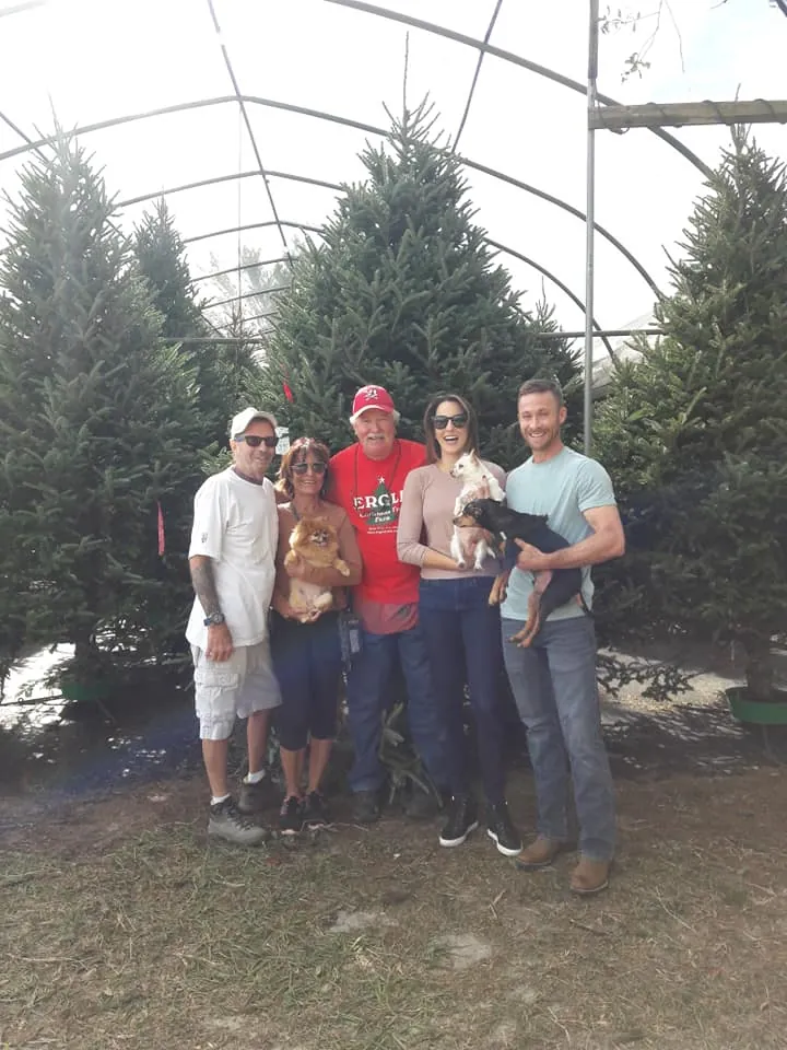 A family holding their small dogs among the trees in the greenhouse