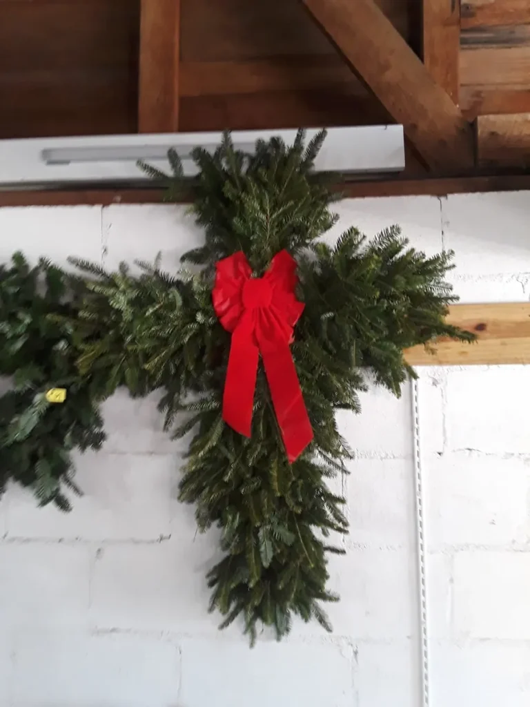 A fresh evergreen swag with a red bow on the barn wall