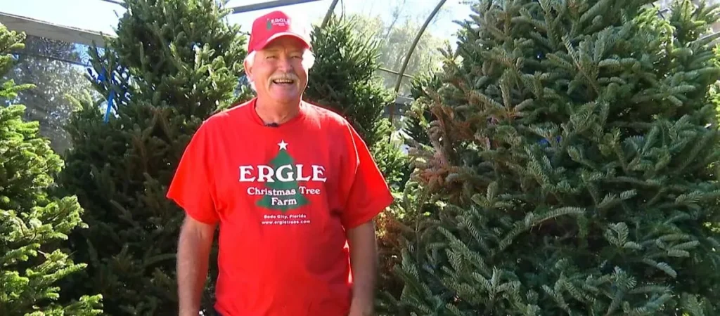 Owner Tony Harris smiling in front of pre-cut Fraser Firs